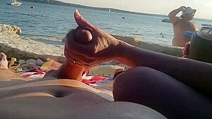 On a nude beach the wife stokes my cock while a voyuer watches