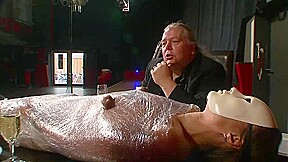 Old and young humiliating slave wrapped in foil on the table